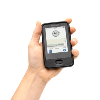 Приймач Dexcom G6 у руці з показниками глюкози на екрані